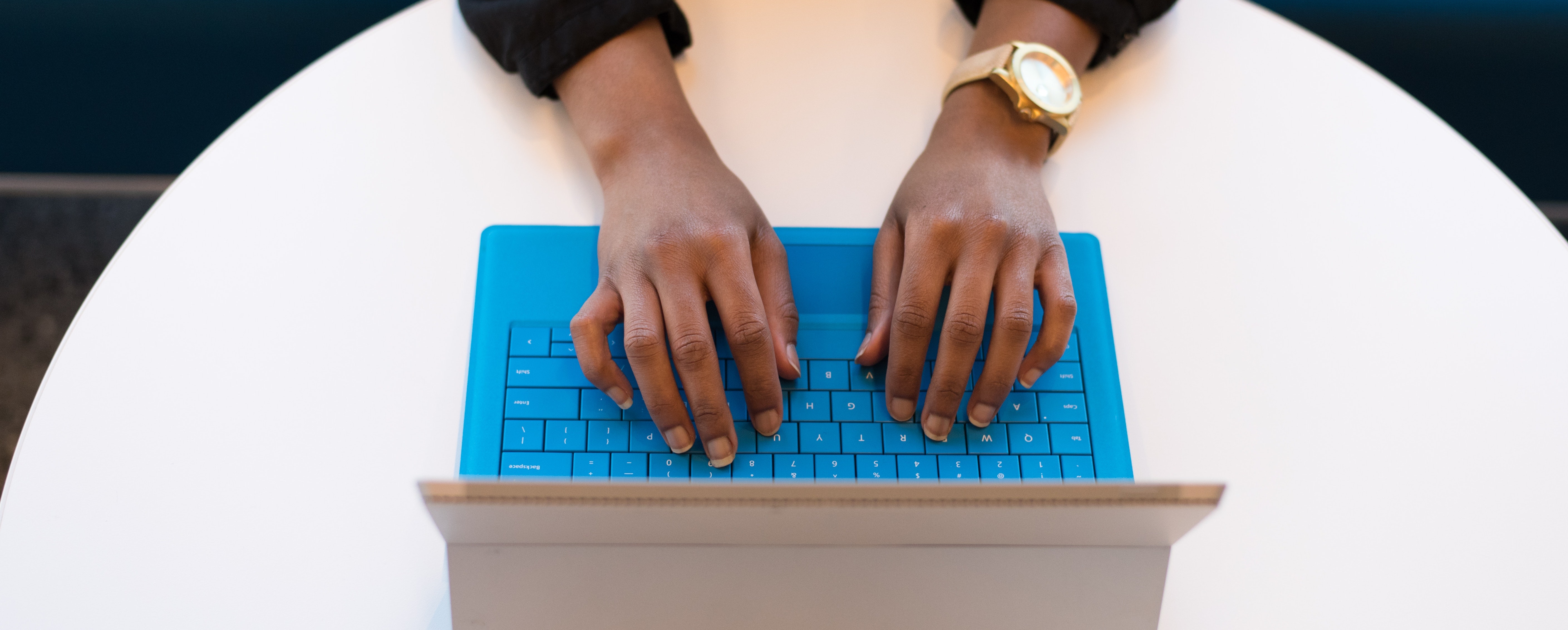 Person typing on blue laptop or tablet keyboard