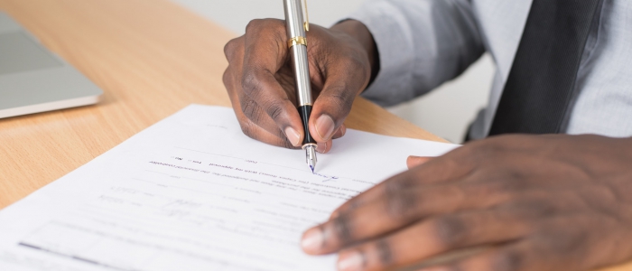 Person completing paper application on table