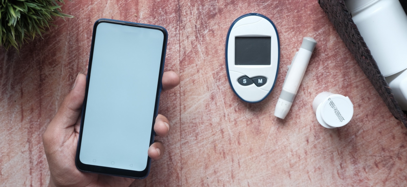 Person holding smartphone next to blood glucose meter