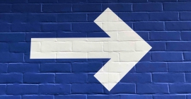 Right pointing white arrow on blue brick wall